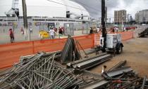 Workers work on areas of infrastructure in front of the construction site of the Arena das Dunas stadium, in Natal May 10, 2014. REUTERS/Nuno Guimaraes