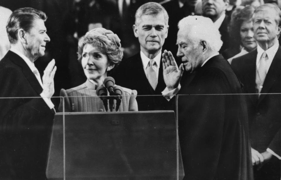 FILE - In this Jan. 20, 1981, file photo Supreme Court Chief Justice Warren Burger administers the oath of office to Ronald Reagan, as Nancy Reagan holds the bible, at the Capitol in Washington. Outgoing President Jimmy Carter and wife Rosalynn look on at right. (AP Photo/Bob Daugherty, File)