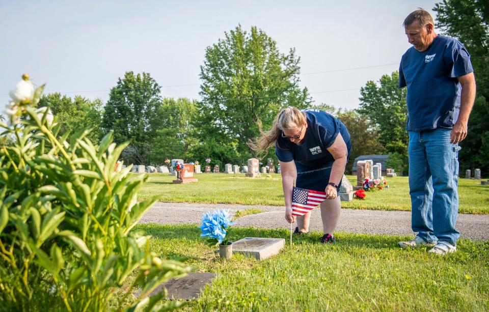 As Auxiliary Conductor Greg Johnson watches, Senior Vice Commander of VFW 604 Cathi Johnson places a flag at a grave at the Presbyterian Cemetery near Ellettsville on Thursday, May 25, 2023.