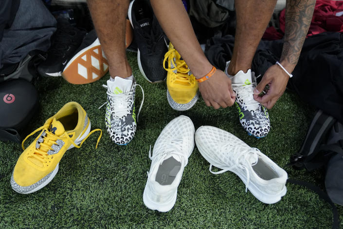 Michigan wide receiver Ronnie Bell changes shoes before he runs a drill at the NFL football scouting combine in Indianapolis, Saturday, March 4, 2023. (AP Photo/Michael Conroy)