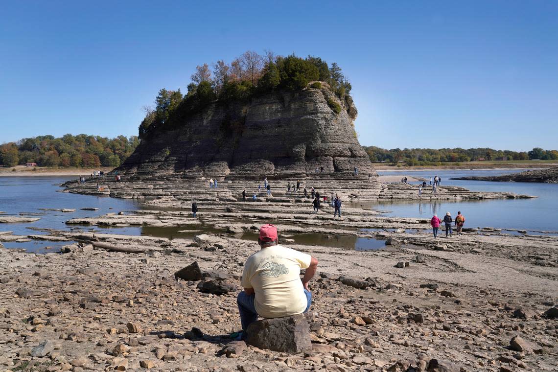 Randy Statler, of Old Appleton, Mo., sits on a rock as he watches as people walk to Tower Rock, an attraction normally surrounded by the Mississippi River and only accessible by boat, Wednesday, Oct. 19, 2022, in Perry County, Mo. Statler, who lives about 10 miles away, says he can only remember one other time the river was so low as to make walking to the rock formation possible.