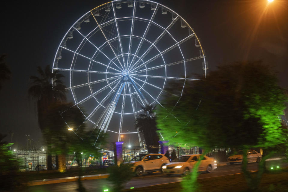 The ferris wheel of Baghdad's Alzawraa amusement park shines in the night in Baghdad, Iraq, Friday, Feb. 24, 2023. Two decades after a U.S.-led invasion, Iraq’s capital today is full of life and a sense of renewal, its residents enjoying a hopeful, peaceful interlude in a painful modern history. (AP Photo/Jerome Delay)