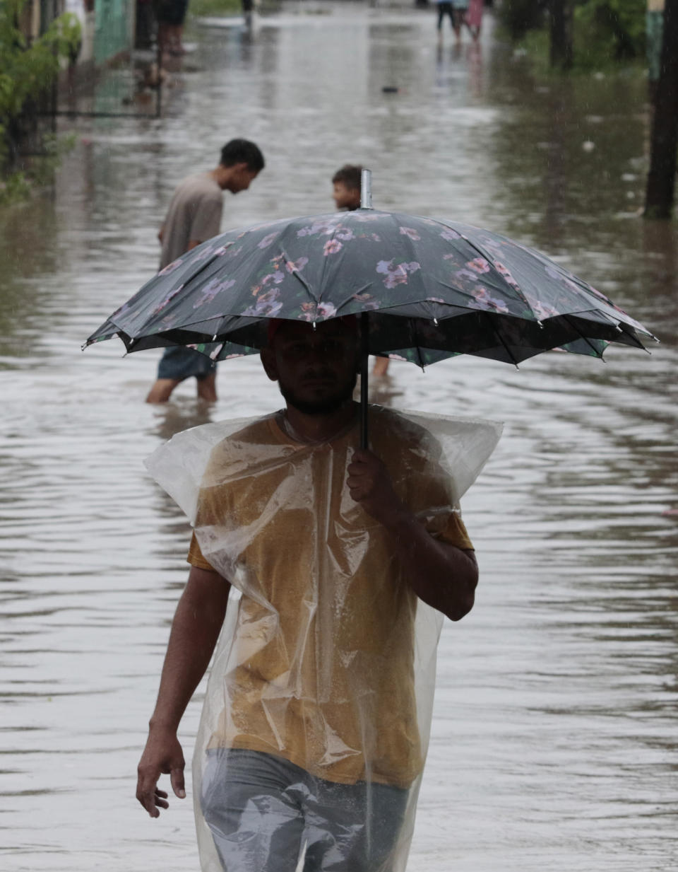 A man, holding an umbrella, walks through floodwaters in San Manuel, Honduras, Wednesday, Nov. 4, 2020. Eta weakened from the Category 4 hurricane to a tropical storm after lashing the Caribbean coast for much of Tuesday, its floodwaters isolating already remote communities and setting off deadly landslides. (AP Photo/Delmer Martinez)