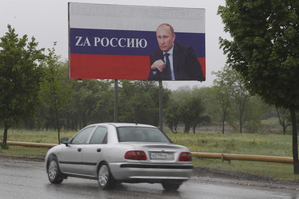 A car drives past a billboard with a portrait of Russian President Vladimir Putin that reads: "For Russia" in Grozny, Russia, Saturday, May 7, 2022. Red Soviet flags and orange-and-black striped military ribbons are on display in Russian cities and towns. Neighborhoods are staging holiday concerts. Flowers are being laid by veterans' groups at monuments to the Great Patriotic War, as World War II is known in the country. At first glance, preparations for Monday's celebration of Victory Day, marking the defeat of Nazi Germany in 1945, seem to be the same as ever. But the mood this year is very different, because Russian troops are fighting and dying again. (AP Photo/Musa Sadulayev)