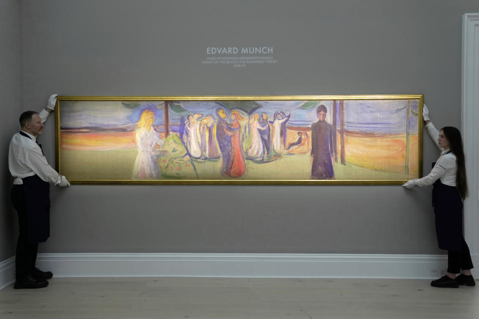 Members of staff hold the four-metre-long painting " Dance on the Beach " by Norwegian painter Edvard Munch, on display during a media preview of Sotheby's auction, in London, Wednesday, Feb. 22, 2023. The piece has an estimated price of 12-20 million pounds and will go on auction on March 1, 2023. (AP Photo/Kin Cheung)