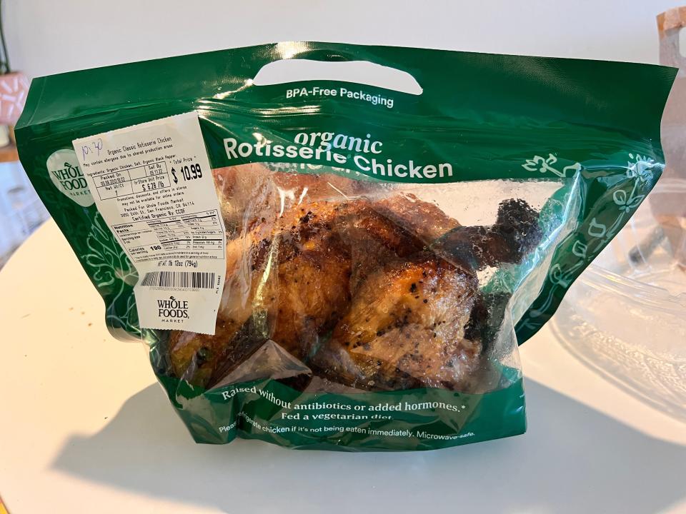 Rotisserie chicken in a clear and green plastic bag with Whole Foods label on outside and visible ingredient list