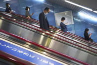 People wearing face masks to help curb the spread of the coronavirus ride an escalator into a subway station in Tokyo Monday, May 11, 2020. Japan has extended a state of emergency until the end of May. (AP Photo/Eugene Hoshiko)