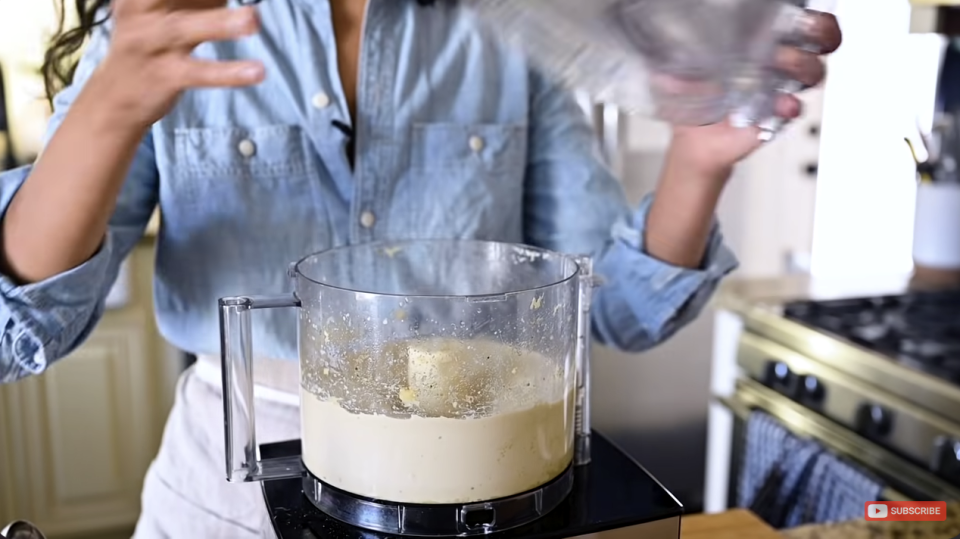 woman making hummus at home in a food processor