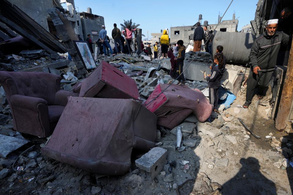 Palestinians look at the destruction of the Al-Gatshan family building after an Israeli strike in Nusseirat refugee camp, central Gaza Strip, on Dec. 18, 2023.