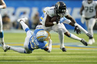 Jacksonville Jaguars running back Travis Etienne Jr. (1) runs against Los Angeles Chargers cornerback Bryce Callahan (23) and safety Nasir Adderley, rear, during the second half of an NFL football game in Inglewood, Calif., Sunday, Sept. 25, 2022. (AP Photo/Marcio Jose Sanchez)