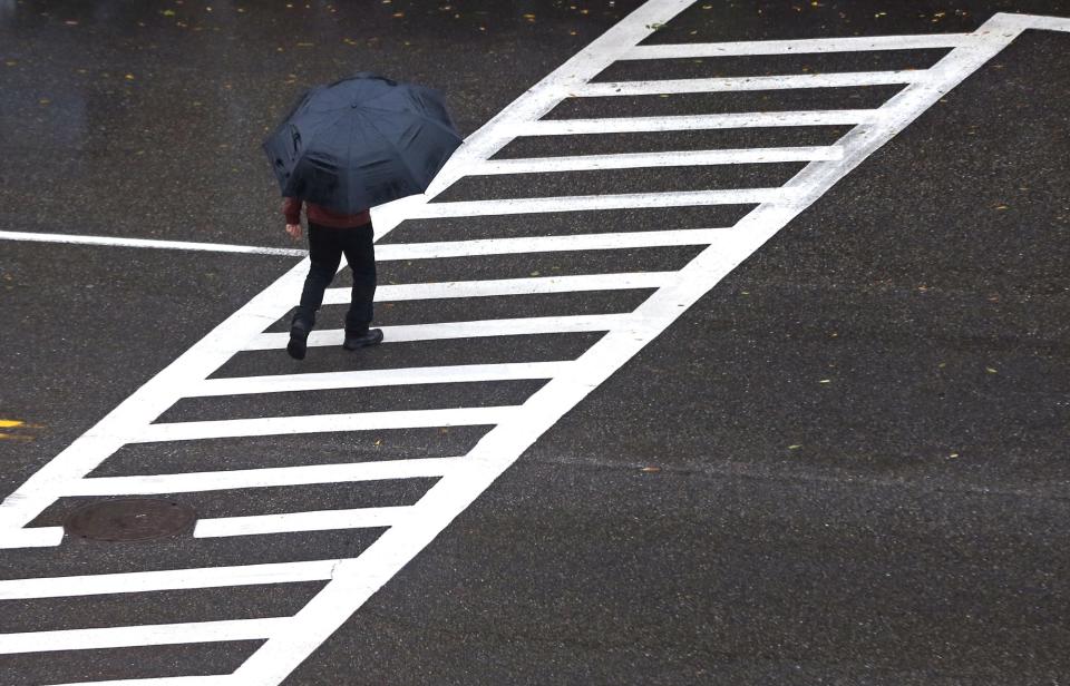 A man is protected by a big umbrella as he crosses Washington Street in the rain in Dover Thursday, Sept. 22, 2022.