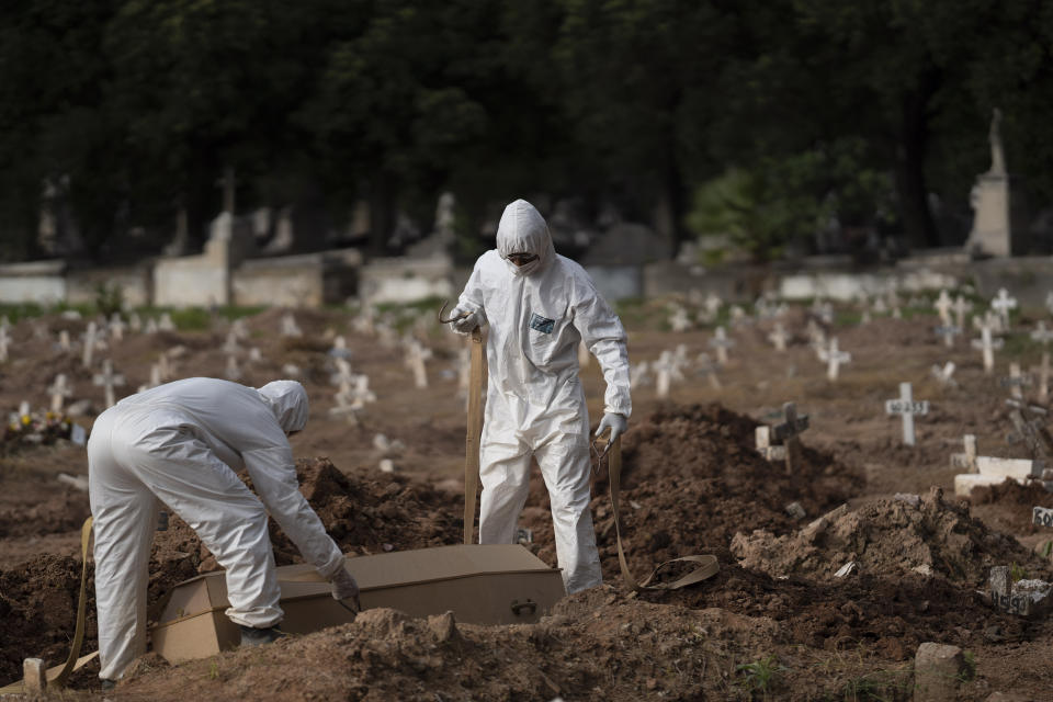 Trabajadores de un cementerio con trajes de protección colocan el ataúd de Paulo Jose da Silva, de 57 años, que murió por el nuevo coronavirus, en Río de Janeiro, Brasil, el viernes 5 de junio de 2020. Según Monique dos Santos, su padrastro se burlaba de la existencia del virus, no llevaba mascarilla, no se cuidaba y quería estrechar la mano con todo el mundo. "No creía en ello y por desgracia encontró su fin. Es muy triste, pero es la verdad", dijo. (AP Foto/Leo Correa)