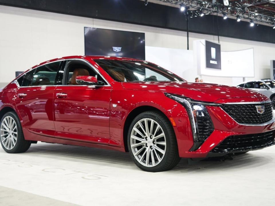 A red sedan sits on a white auto show floor.