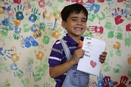 Jean Paul Valera, 6, holds a drawing he drew which depicts the late Venezuelan President Hugo Chavez, during a writing workshop at 4F military fort in Caracas, December 14, 2014. REUTERS/Carlos Garcia Rawlins