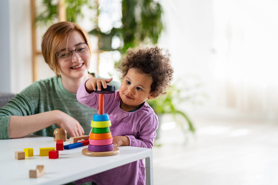 babysitter playing with stacking blocks with toddler