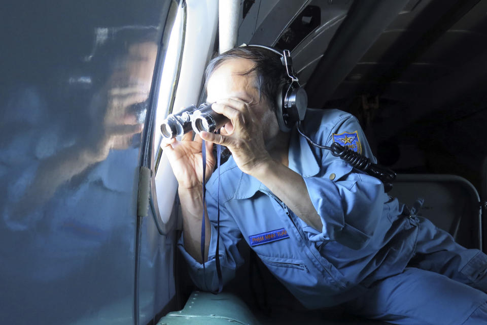 Vietnamese Air Force Col. Pham Minh Tuan uses binoculars on board a flying aircraft during a mission to search for the missing Malaysia Airlines flight MH370 in the Gulf of Thailand over the location where Chinese satellite images showed possible debris from the missing Malaysian jetliner, Thursday, March 13, 2014. (AP Photo)