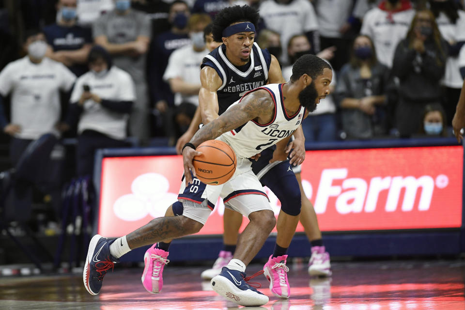 Connecticut's R.J. Cole dribbles around Georgetown's Dante Harris, back, in the first half of an NCAA college basketball game, Tuesday, Jan. 25, 2022, in Storrs, Conn. (AP Photo/Jessica Hill)