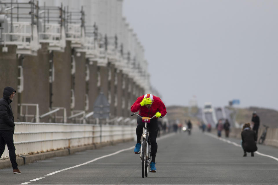 A competitor holds onto his cap as he battles gale force winds during the Dutch Headwind Cycling Championships on the storm barrier Oosterscheldekering near Neeltje Jans, south-western Netherlands, Sunday, Feb. 9, 2020. (AP Photo/Peter Dejong)