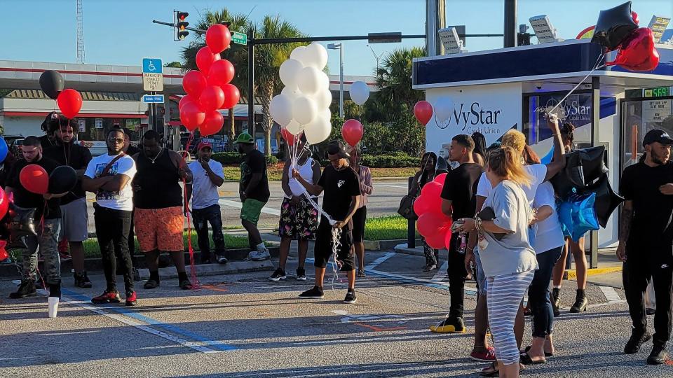Gathering next to the Bowden Road ATM where Jamarion Barnes and Tyniya Powell were shot late Monday in Jacksonville, family and friends support Barnes' mother, Terri Lauramore (partially concealed to the right), prior to a balloon launch. The memorial also was for Jelijah Barnes, Jamarion's brother who was killed in March.