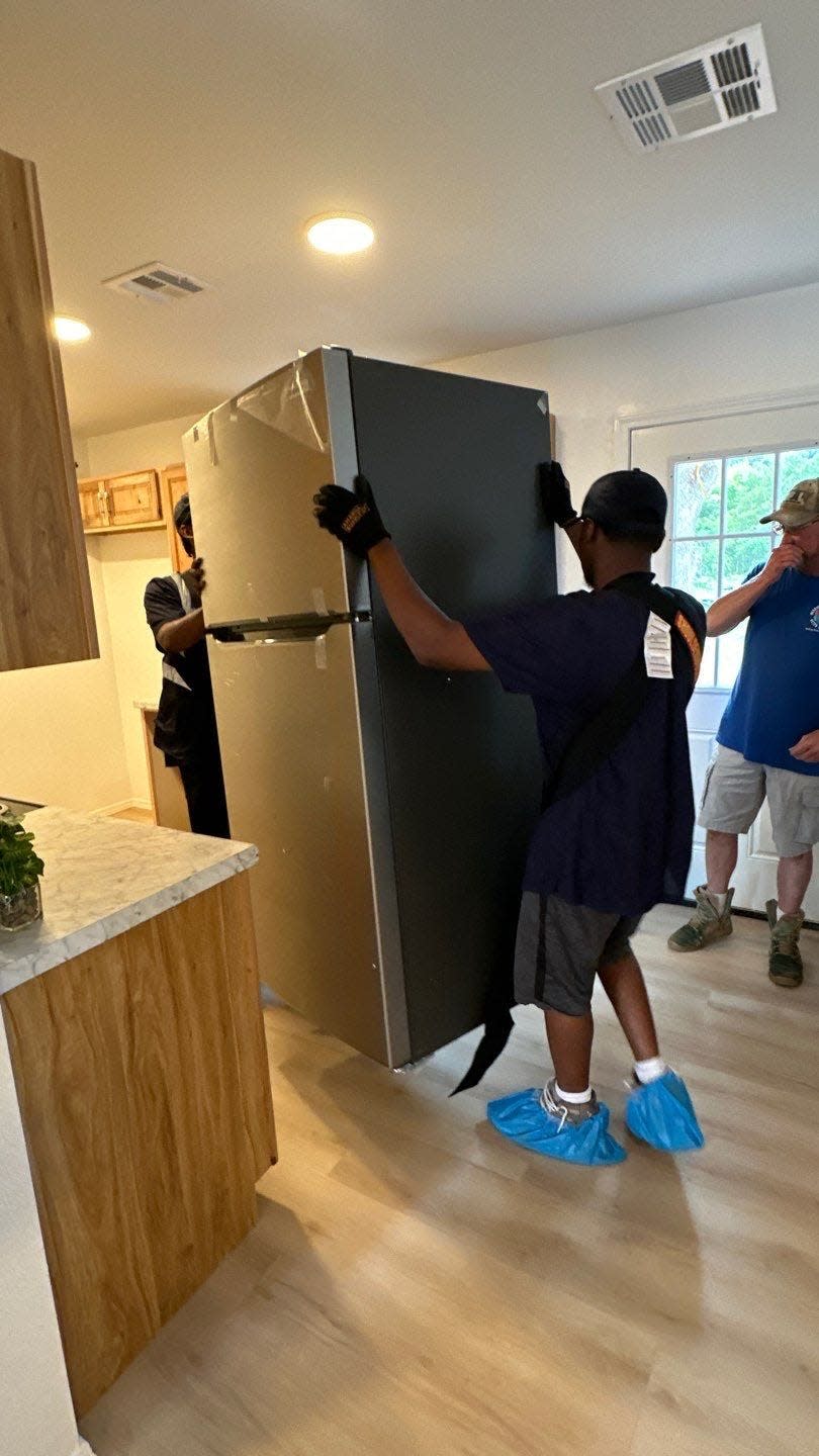 Volunteers place a refrigerator in a new home built for a Slaughterville woman and her son, whose former house had received extensive storm damage.
