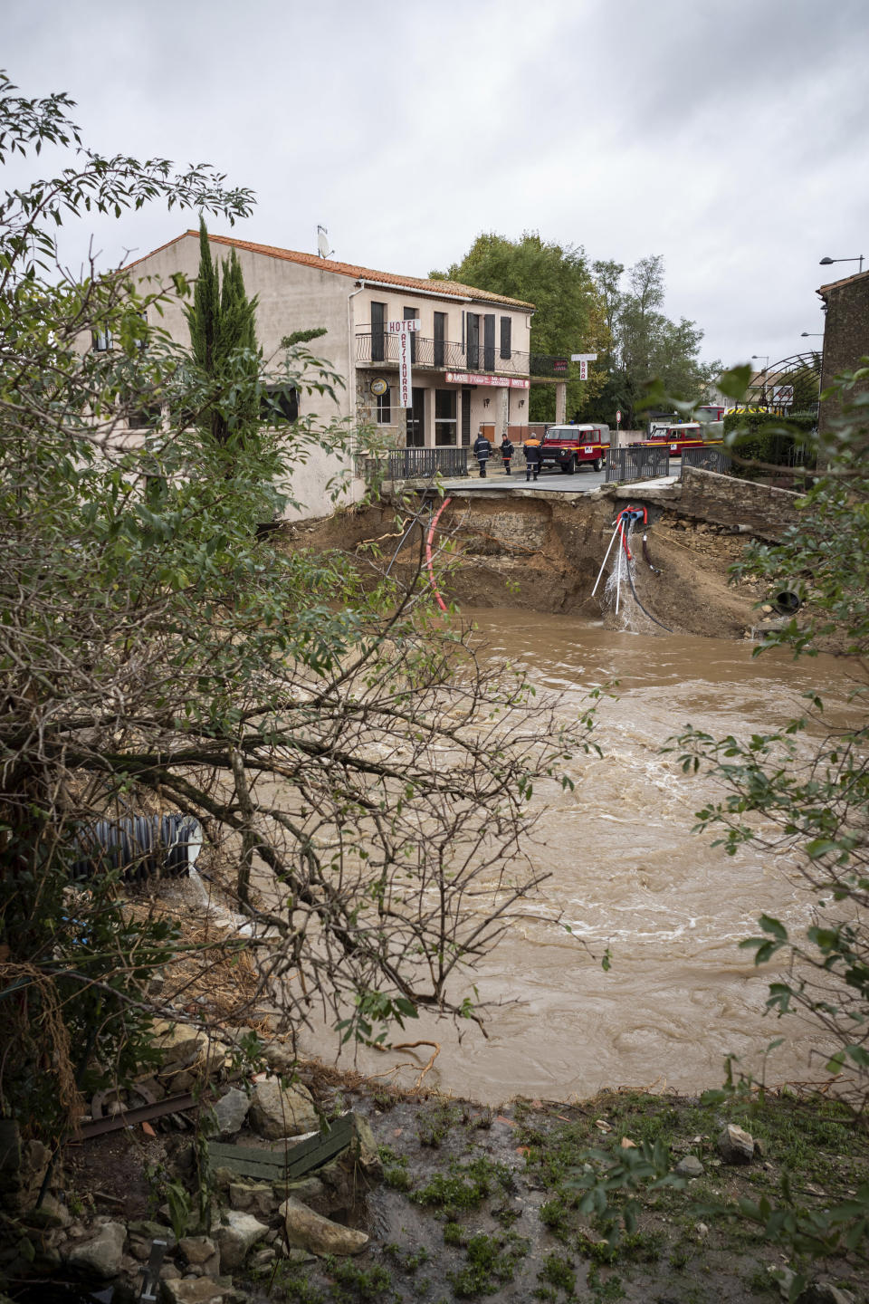 Rescue workers, background, secure the area by a collapsed bridge after flash floods in the town of Villegailhenc, southern France, Monday, Oct.15, 2018. Flash floods tore through towns in southwest France, turning streams into raging torrents that authorities said killed several people and seriously injured at least five others. (AP Photo/Fred Lancelot)