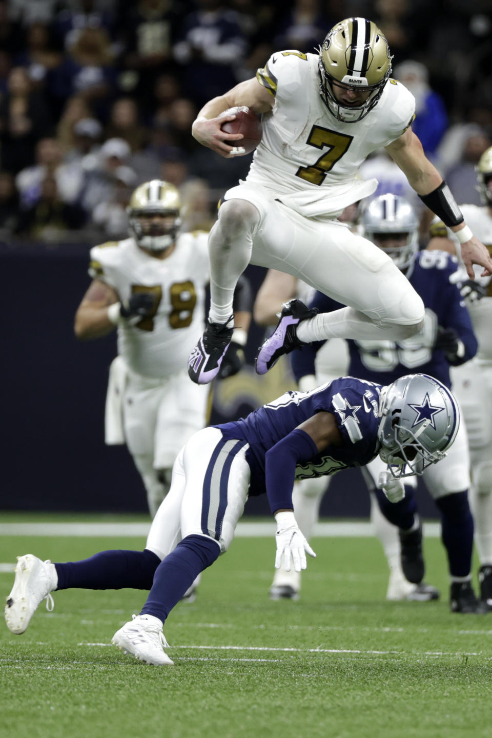 New Orleans Saints quarterback Taysom Hill (7) leaps over Dallas Cowboys free safety Damontae Kazee (18) during the second half of an NFL football game, Thursday, Dec. 2, 2021, in New Orleans. (AP Photo/Derick Hingle)