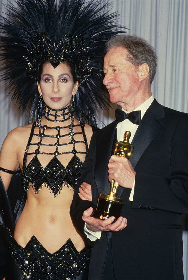 Cher in a headdress and black, revealing dress at the '86 Oscars