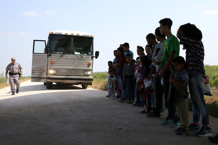 FILE PHOTO: Immigrants who turned themselves in to border patrol agents after illegally crossing the border from Mexico into the U.S. wait to be transported for processing in the Rio Grande Valley sector, near McAllen, Texas, U.S., April 2, 2018. Picture taken April 2, 2018. REUTERS/Loren Elliott/File Photo