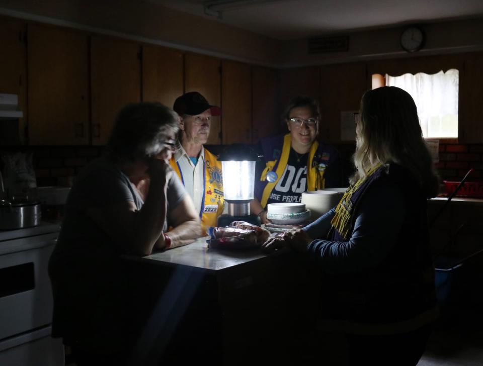 Volunteers Ada Wood, Roger Comeau, Christina Chafe and Karen Tracey, with the Eastern Charlotte Lions Club, huddle around a lantern in the kitchen of the Pennfield Lions Club.  