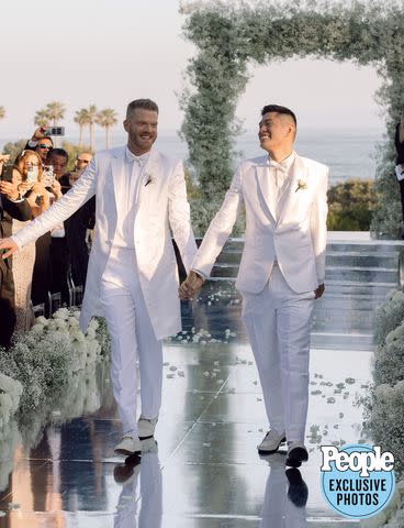 <p>HEATHER KINCAID PHOTOGRAPHER</p> Scott Hoying (left) and Mark Manio walk down the aisle after tying the knot.