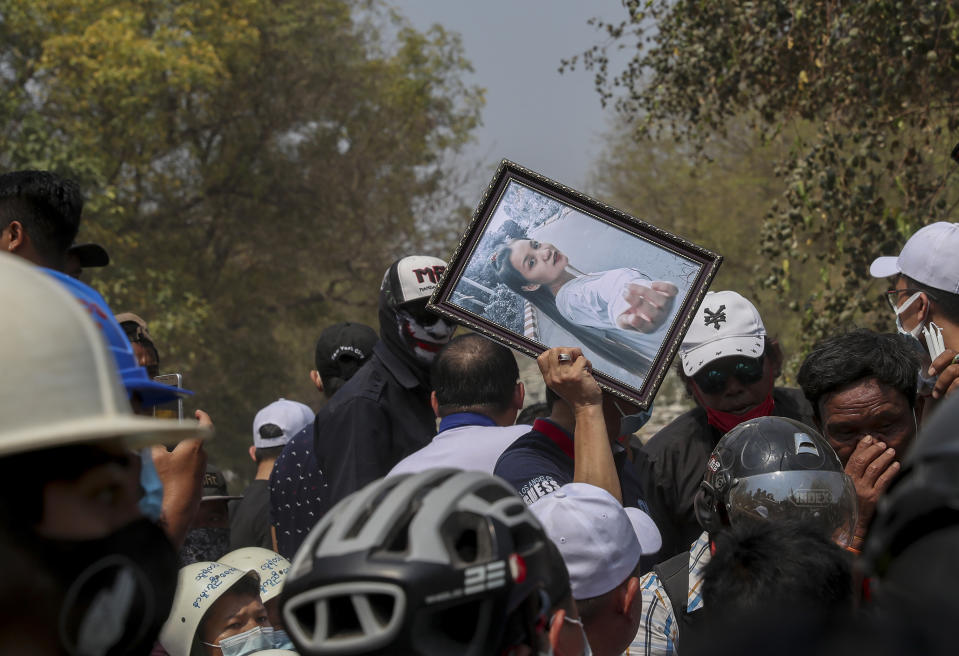 FILE - In this Thursday, March 4, 2021 file photo, a man holds a picture of 19-year-old Kyal Sin, also known as Angel, during her burial in Mandalay, Myanmar. Authorities released a death certificate saying the bullet that killed her didn’t match the caliber used by police, that it came from the wrong direction for security forces to be responsible, and blamed protesters for her death. However, local news reports and social media accounts said security forces were firing live rounds. (AP Photo)