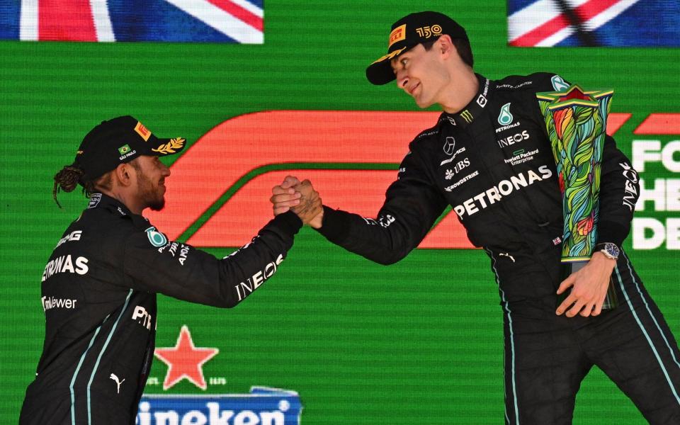 Mercedes' British driver George Russell (R) celebrates on the podium with his teammate second-placed driver Lewis Hamilton after winning the Formula One Brazil Grand Prix at the Autodromo Jose Carlos Pace racetrack, - Nelson Almeida/Getty Images