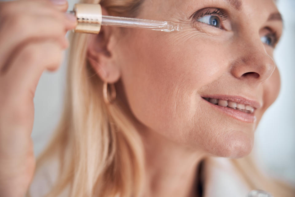 Mature woman applying peptide serum to fine lines