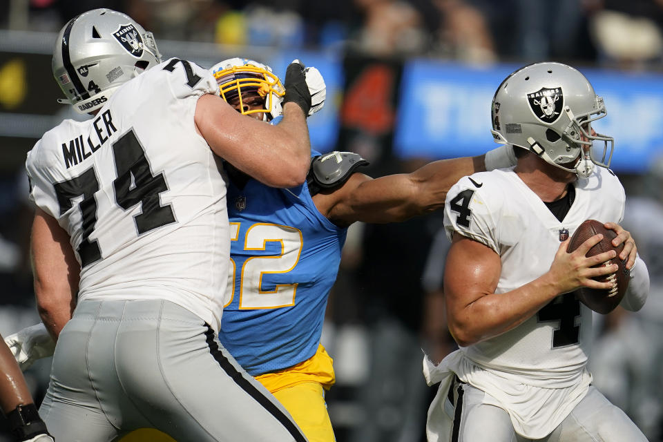 Los Angeles Chargers linebacker Khalil Mack, middle, reaches for Las Vegas Raiders quarterback Derek Carr (4) while being blocked by offensive tackle Kolton Miller (74) during the second half of an NFL football game in Inglewood, Calif., Sunday, Sept. 11, 2022. (AP Photo/Marcio Jose Sanchez)