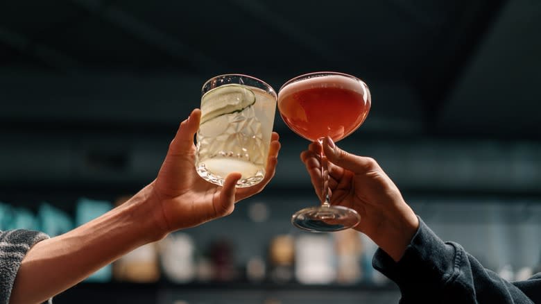 people holding and clinking cocktails