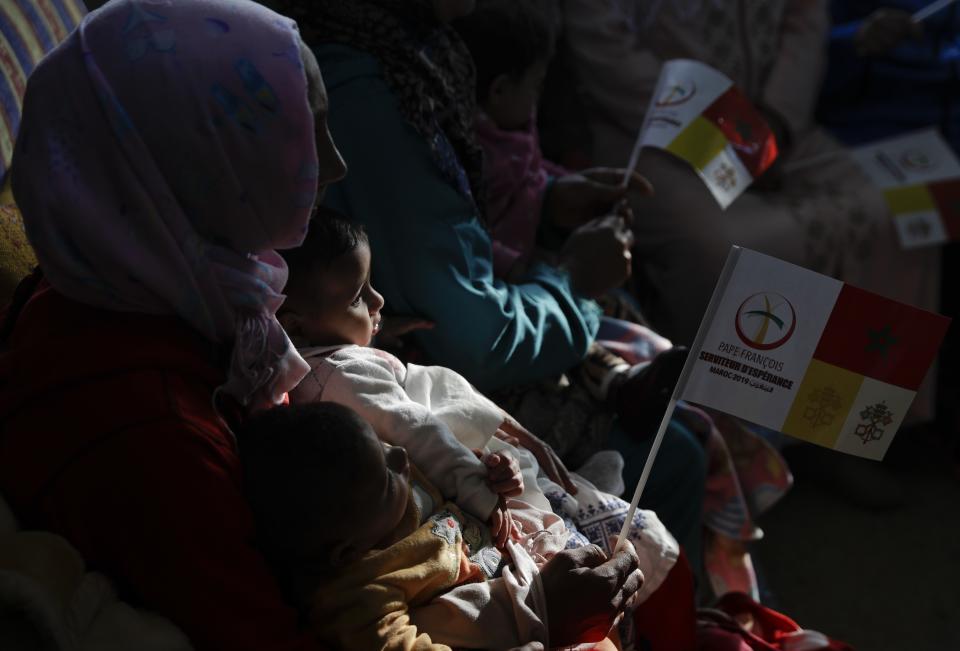 A woman holds her child as they wait for Pope Francis to arrive at the Rural Center for Social Services at Temara, south of Rabat, Morocco, Sunday, March 31, 2019. Pope Francis is in Morocco for a two-day trip aimed at highlighting the North African nation's Christian-Muslim ties, while also showing solidarity with migrants at Europe's door and tending to a tiny Catholic flock. (AP Photo/Gregorio Borgia)