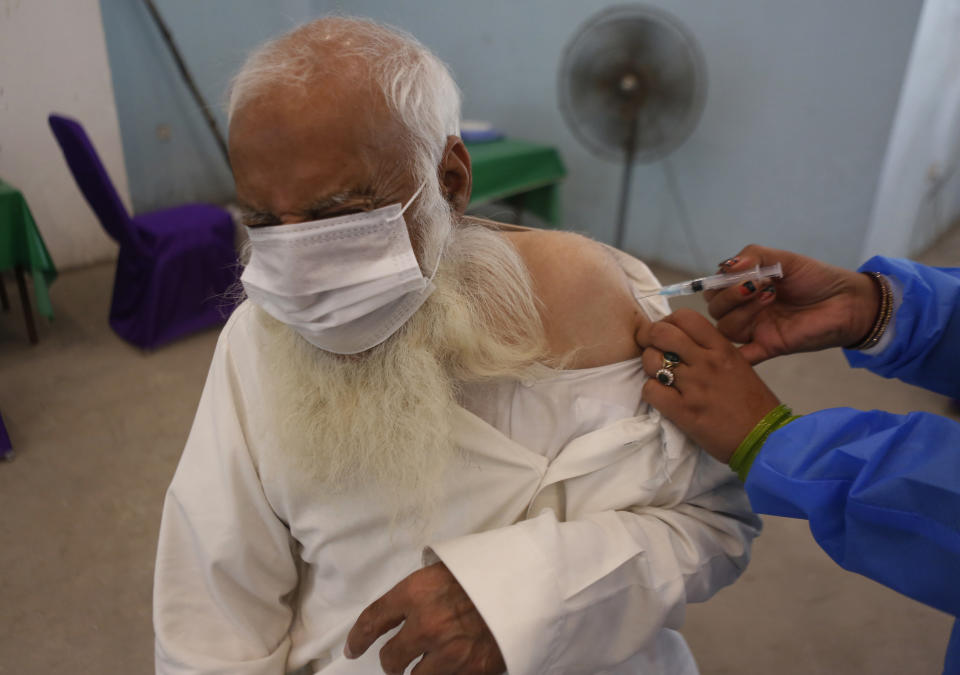 A man reacts while receiving a Sinopharm coronavirus vaccine from a health worker at a vaccination center in Lahore, Pakistan, Monday, March 29, 2021. (AP Photo/K.M. Chaudary)