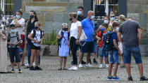 FILE - In this Wednesday, Aug. 12, 2020 file photo, parents wait with their children for the start of their first day of school in Gelsenkirchen, Germany. Despite a spike in coronavirus infections, authorities in Europe are determined to send children back to school. At least 41 of Berlin’s 825 schools reported virus cases as classes resumed this month, and thousands of students have been quarantined around the country. But Germany is determined not to close schools anew, so they're sending individual students or classes into quarantine instead. (AP Photo/Martin Meissner, File)