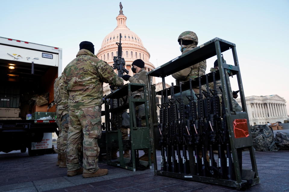 Members of the National Guard are given weapons at the back of an open truck in front of the Capitol