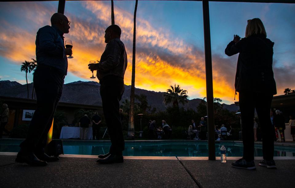 Guests mingle as the sun sets behind the mountains during a party at Frank Sinatra's Twin Palms estate held in tribute to Sinatra’s friend, American film and dance star Gene Kelly, in Palm Springs, Calif., Saturday, Feb. 26, 2022.