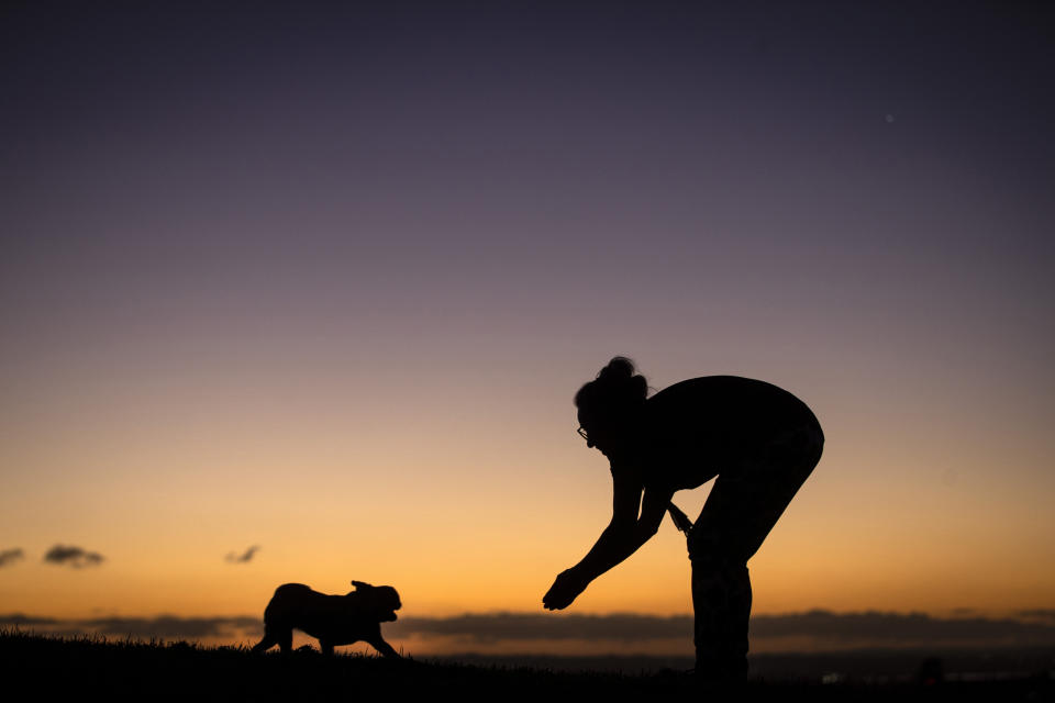 Rachel Ashton plays with her pug, Frankie, on the summit of Mount Roskill as the sunsets on a crisp winter evening in Auckland, New Zealand, on June 23, 2021. New Zealand has recorded its warmest June since recordkeeping began, as ski fields struggle to open and experts predict shorter southern winters in the future. (Jason Oxenham/New Zealand Herald via AP)