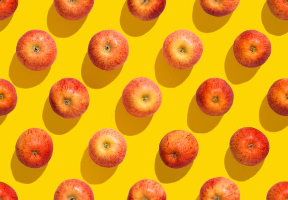 Evenly spaced apples on a yellow background