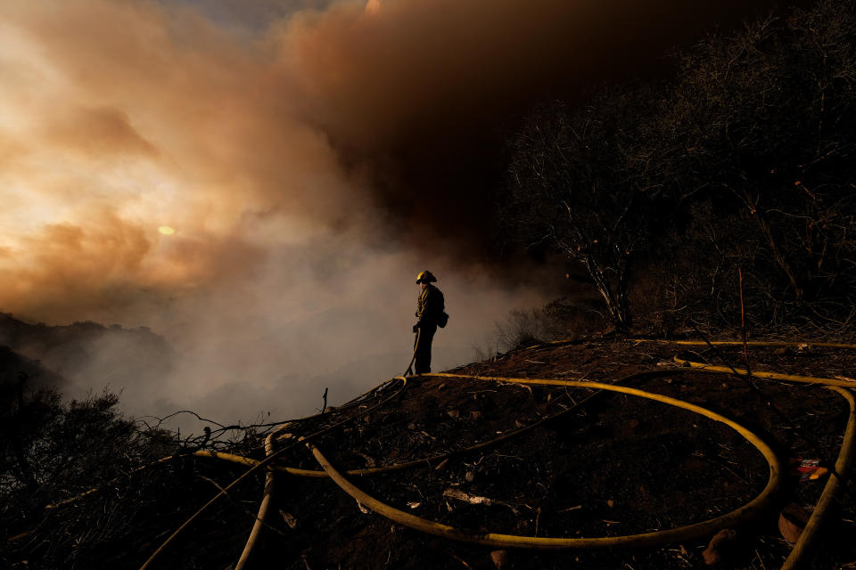 A firefighter keeps watch as smoke rises from a brush fire scorching at least 100 acres in the Pacific Palisades area of Los Angeles on Saturday, May 15, 2021. (AP Photo/Ringo H.W. Chiu)
