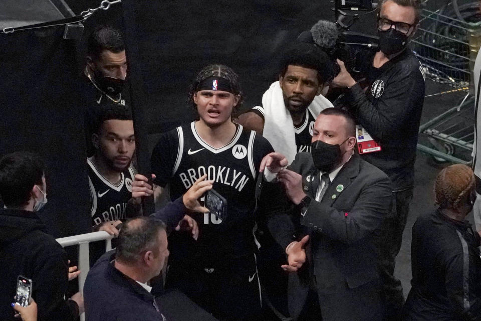 FILE - A security guard points as Brooklyn Nets' Kyrie Irving, right with towel, and teammates look up at a fan who reportedly threw a water bottle at him as he left the court after Game 4 during an NBA basketball first-round playoff series in Boston, in this Sunday, May 30, 2021, file photo. Mindful of high-profile incidents of unruly fan behavior in recent years, the NBA has partnered with the National District Attorneys Association to connect franchises with prosecutors who can serve as points of contact with teams when misconduct occurs. (AP Photo/Elise Amendola, File)