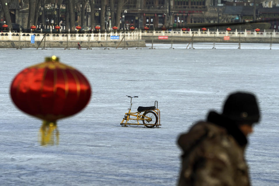 A worker walks by a specially made steel sled parked alone on the capital popular ice skating frozen Houhai Lake after it was ordered to close following the coronavirus cases surge, in Beijing, Thursday, Jan. 21, 2021. China is making some of its toughest travel restrictions yet as coronavirus cases surge in several northern provinces ahead of the travel rush for Lunar New Year next month. (AP Photo/Andy Wong)