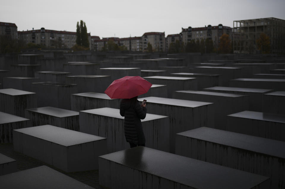 A woman with a red umbrella visits the Memorial for the murdered Jews of Europe, the so called Holocaust Memorial in central Berlin, Germany, Monday, Nov. 1, 2021. Berlin's police chief apologized for an incident in which officers were seen practising press-ups at the German capital's memorial to the 6 million Jews killed in the Nazi Holocaust. (AP Photo/Markus Schreiber)