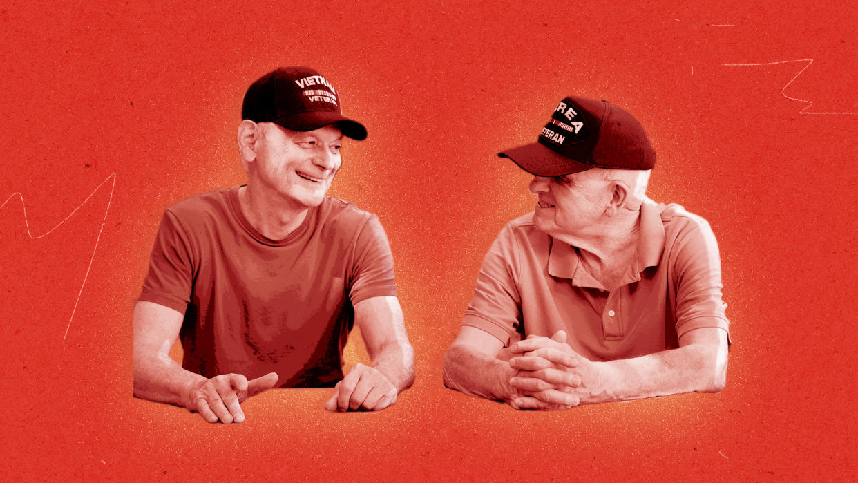 Two older men wearing veterans' baseball caps, one for Vietnam and one for Korea, chatting congenially. 