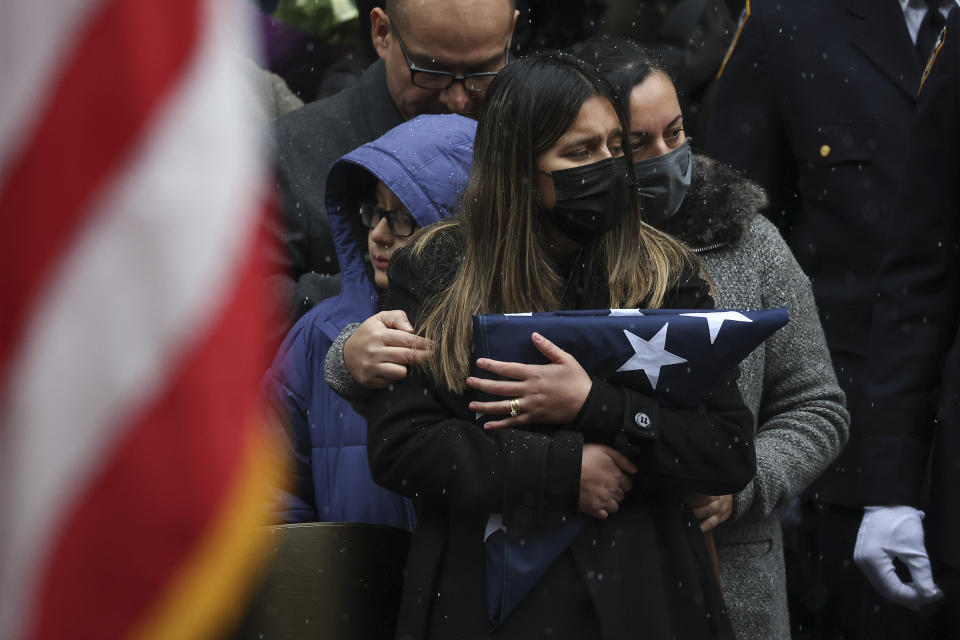 Dominique Rivera, left, wife of, NYPD Officer Jason Rivera watches as his casket is loaded into a hearse outside St. Patrick's Cathedral after his funeral service, Friday, Jan. 28, 2022, in New York. Rivera and his partner, Officer Wilbert Mora, were fatally wounded when a gunman ambushed them in an apartment as they responded to a family dispute last week. (AP Photo/Yuki Iwamura)