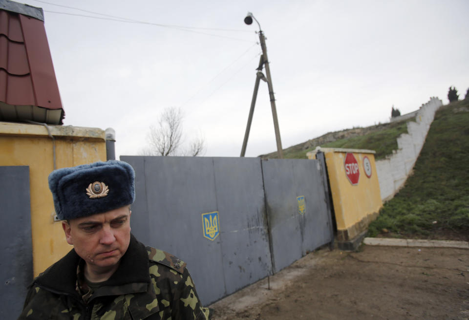 A Ukrainian officer stands outside the gate of a military base at the Black Sea port of Sevastopol in Crimea, Ukraine, Saturday, March 8, 2014. A Ukrainian officer at the military base said that pro-Russia soldiers crashed a truck through its gates late on Friday in an attempt to take it over. (AP Photo/Darko Vojinovic)