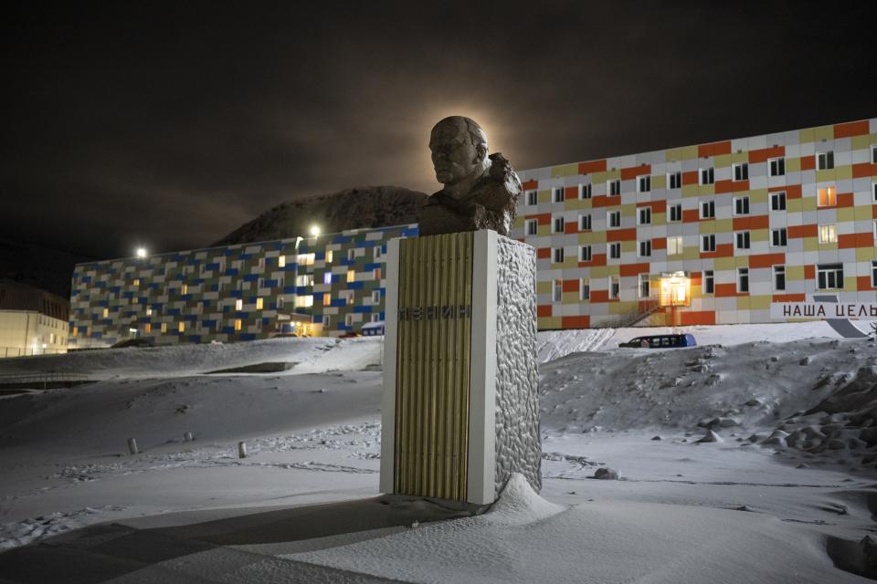 A full moon rises behind a statue of Lenin in Barentsburg, Norway, Saturday, Jan. 7, 2023. About 350 people live in Barentsburg, the village owned by Russia's Arctic mining company in the remote Norwegian territory. (AP Photo/Daniel Cole)